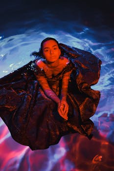 一幅艺术肖像中，一位身着深色布料的女人沉浸在忧郁的蓝紫光芒里