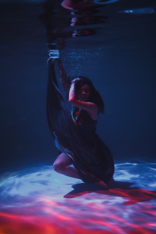 Free Elegant woman submerged underwater in a dramatic, colorful scene. Stock Photo