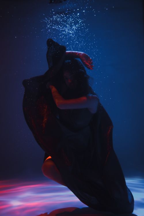 Free Artistic underwater photograph capturing a graceful model with flowing fabric in vivid lighting. Stock Photo