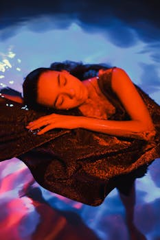 一个女人平静地漂浮在充满活力的蓝橙相间的水中，营造出梦幻而宁静的氛围