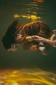 一位女子在水下优雅地摆出姿势，营造出梦幻的艺术效果