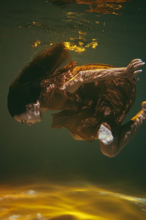 Free Artistic underwater photo of a woman gracefully submerged in a flowing dress. Stock Photo
