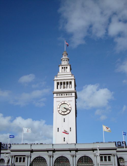 Free Iconic clock tower architecture against a bright blue sky, featuring prominent flags. Stock Photo