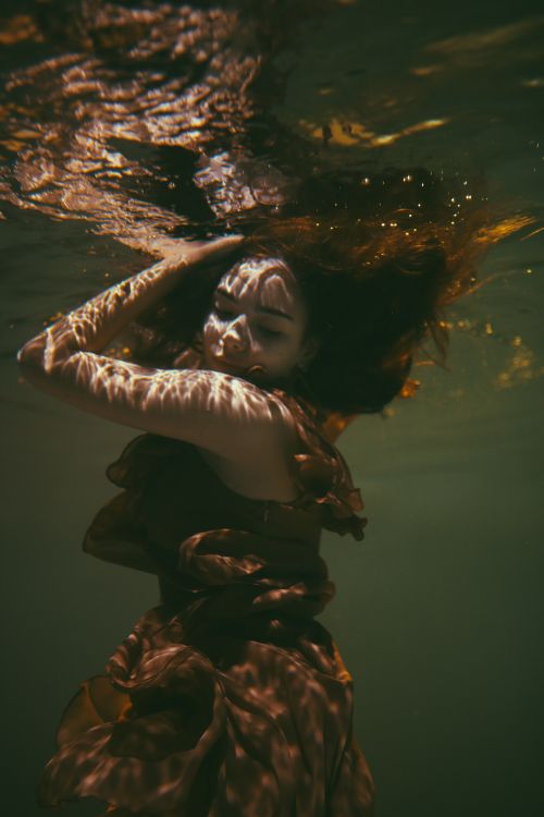 Free Artistic underwater portrait of a woman in a dress, reflecting melancholy and beauty. Stock Photo
