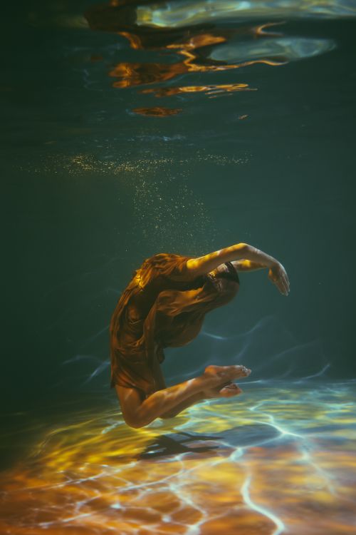 Free A woman artistically posing underwater, showcasing grace and movement in a flowing dress. Stock Photo