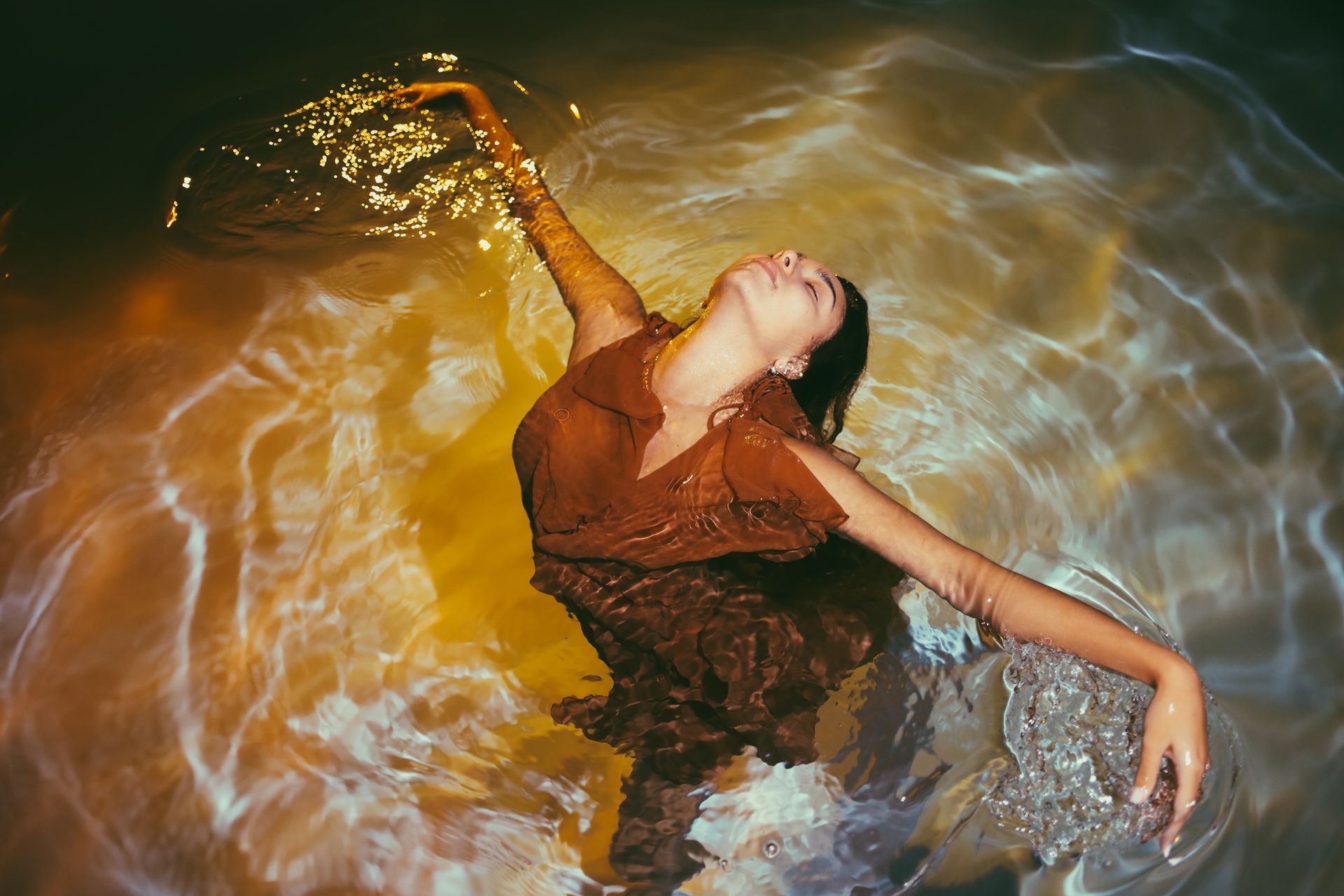 A woman gracefully moves in water, creating captivating ripples and reflections.