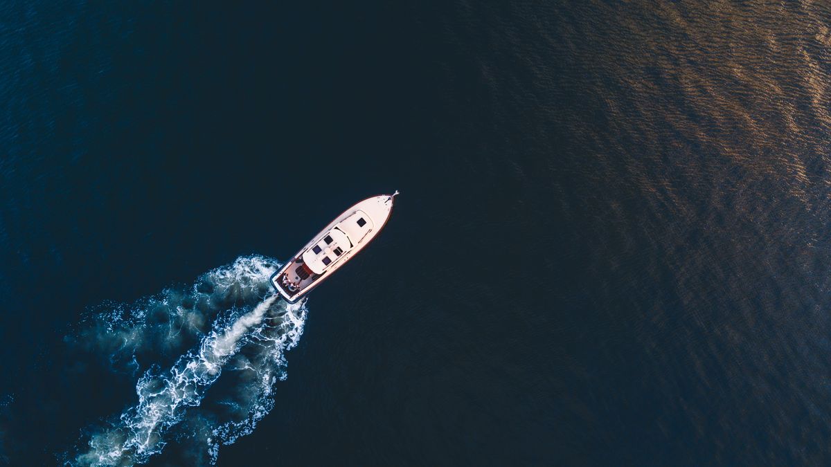 Yacht cutting a white wake across dark blue water