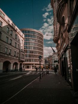 Perspective view of street with historic and contemporary building facades under cloudy sky in city