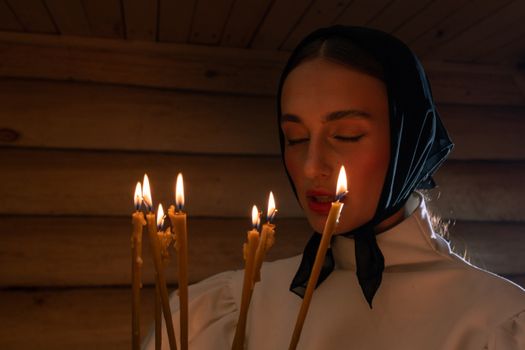 一位闭着眼睛的宁静女人手持点燃的蜡烛，感受着温暖的拥抱