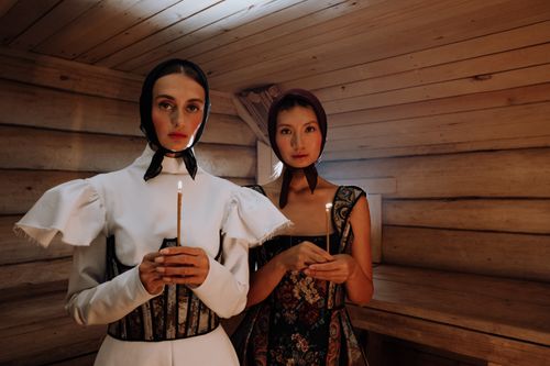 Free Two women in traditional attire holding candles in a wooden room. Stock Photo