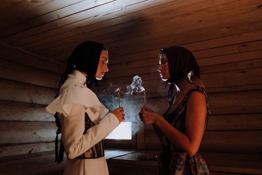 在一间木房内，两名女子手持香烛，四周烟雾缭绕，营造出一种神秘的氛围