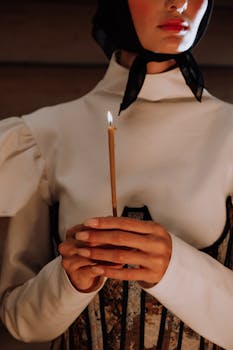 Close-up of a woman holding a lit candle in traditional attire.