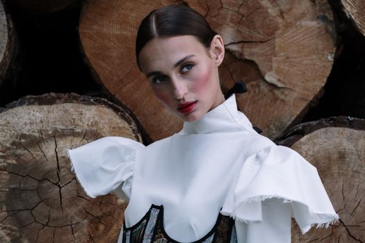 Model in white dress by a log backdrop