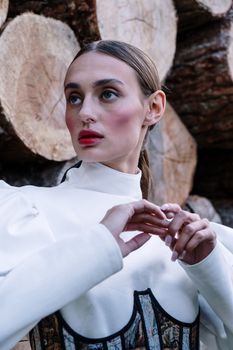 Striking model poses elegantly in white attire against a natural wood backdrop.
