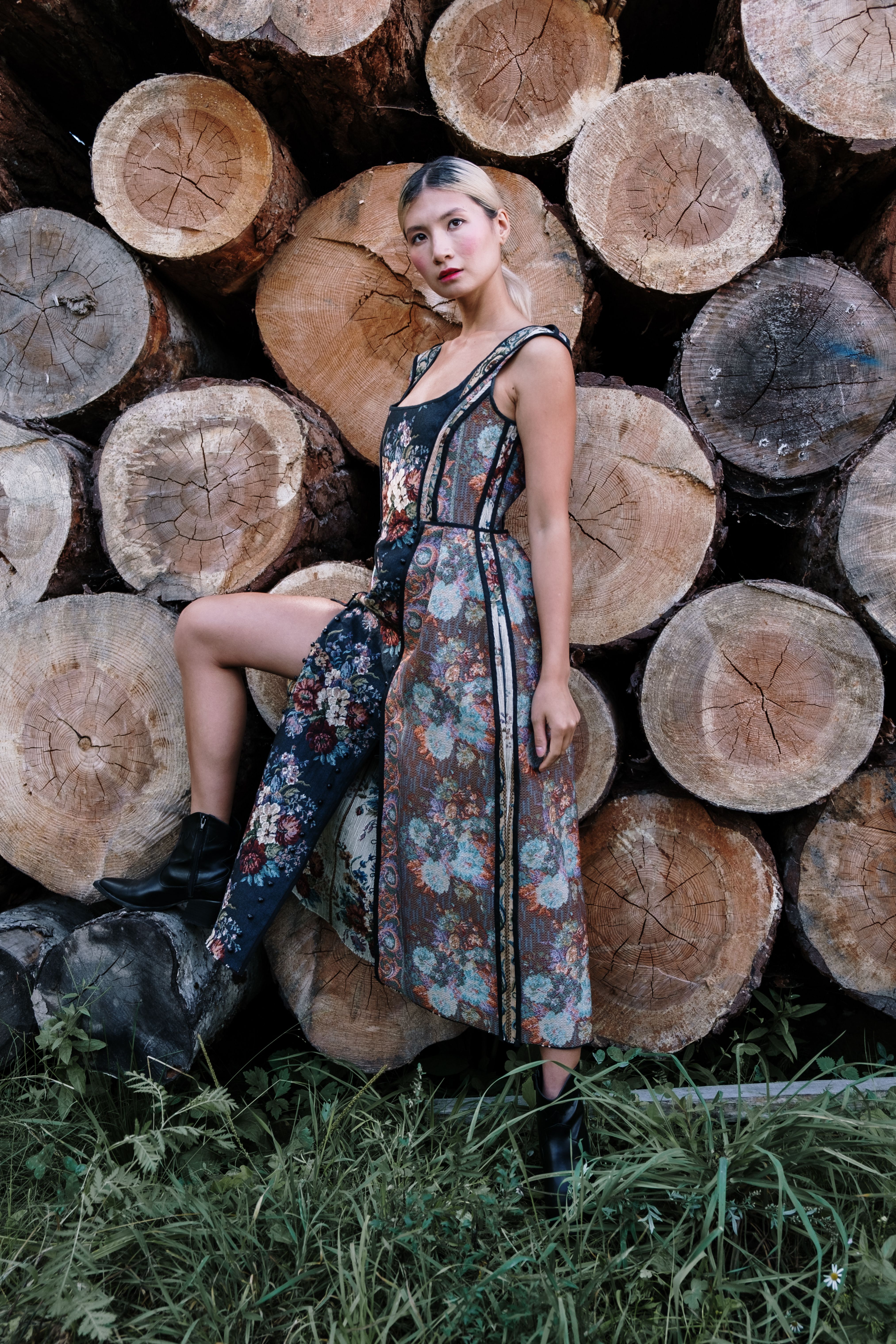 Woman in a Floral Dress Standing in Front of Wooden Logs · Free Stock Photo