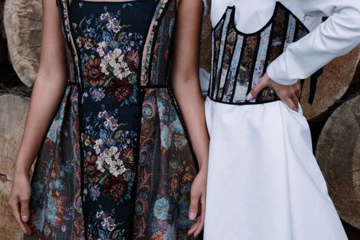 Close-up of two stylish floral dresses with intricate designs and patterns outdoors.