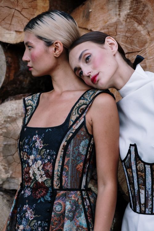 Free Two stylish women in high fashion outfits posing outdoors by textured wood background. Stock Photo