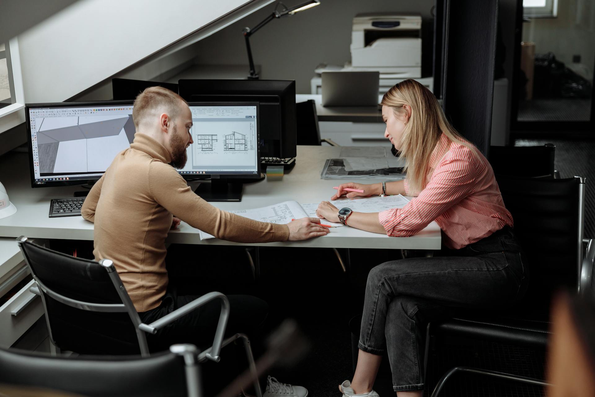 Two architects discuss plans in a contemporary office, focusing on project details.