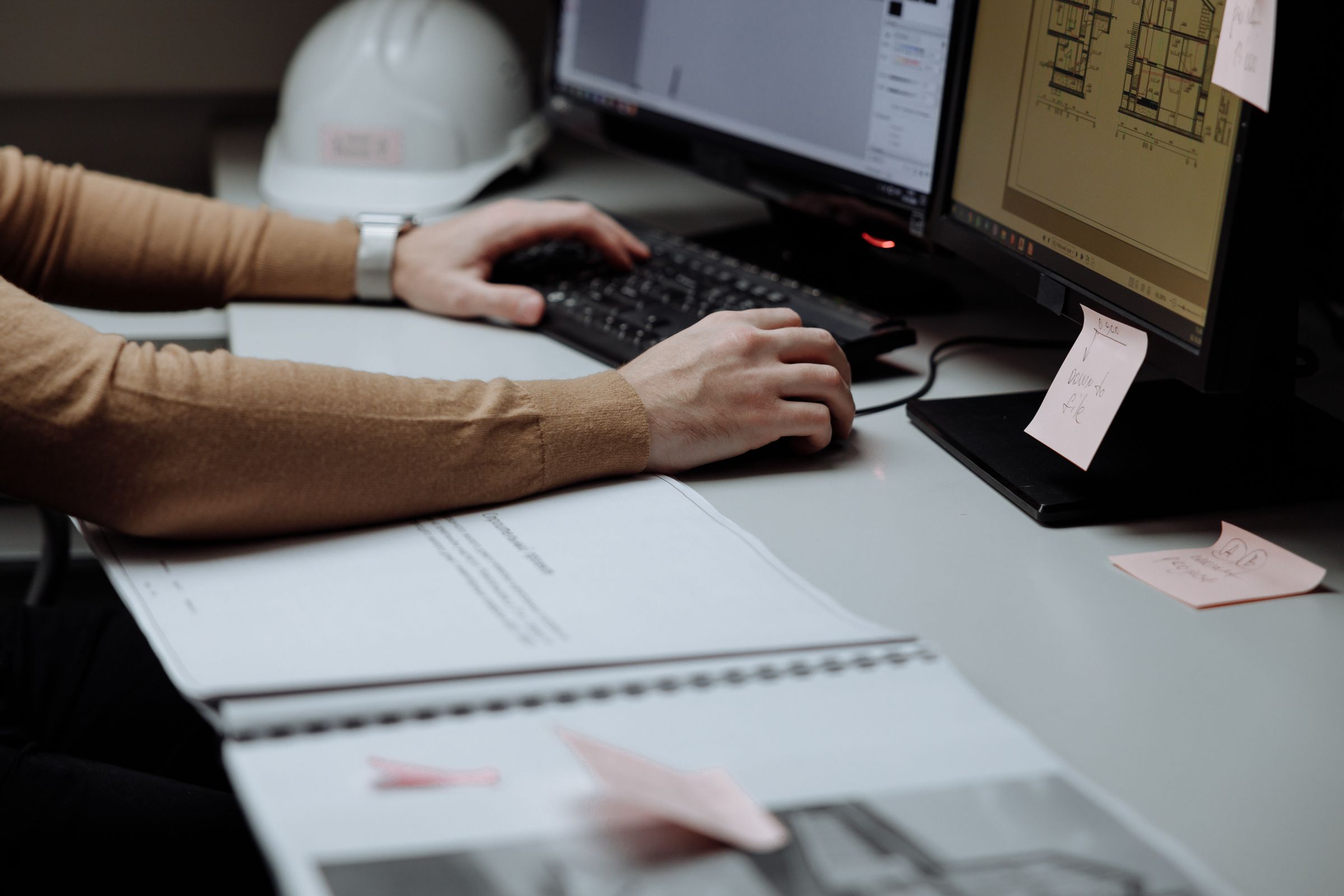 Architect focused on digital design at dual monitors in a modern workspace