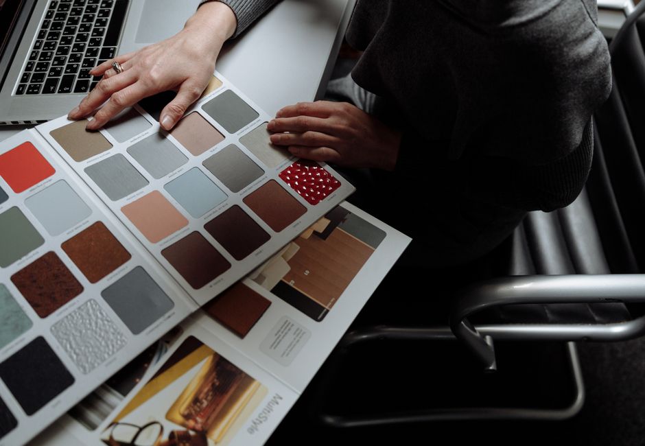 Interior designer on laptop reviewing color swatches for design project. Overhead view, modern workspace.