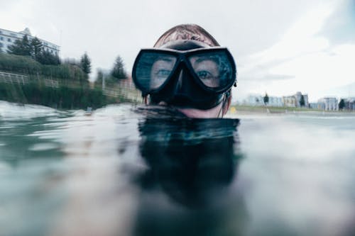 Young female floating in snorkeling mask in crystal clear water of sea during vacation