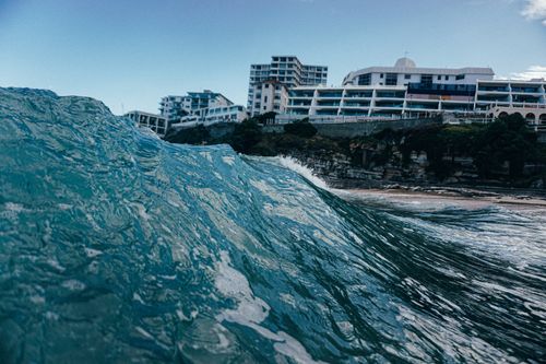 Free High wave of blue sea rolling near sandy coast at resort with hotels Stock Photo