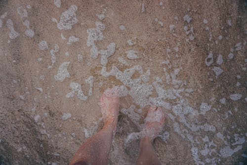 Man standing on sand in clear foaming water