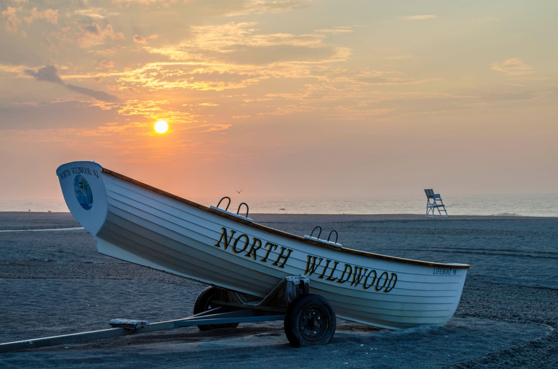 Beautiful sunrise at North Wildwood Beach with a lifeguard boat on the sand.