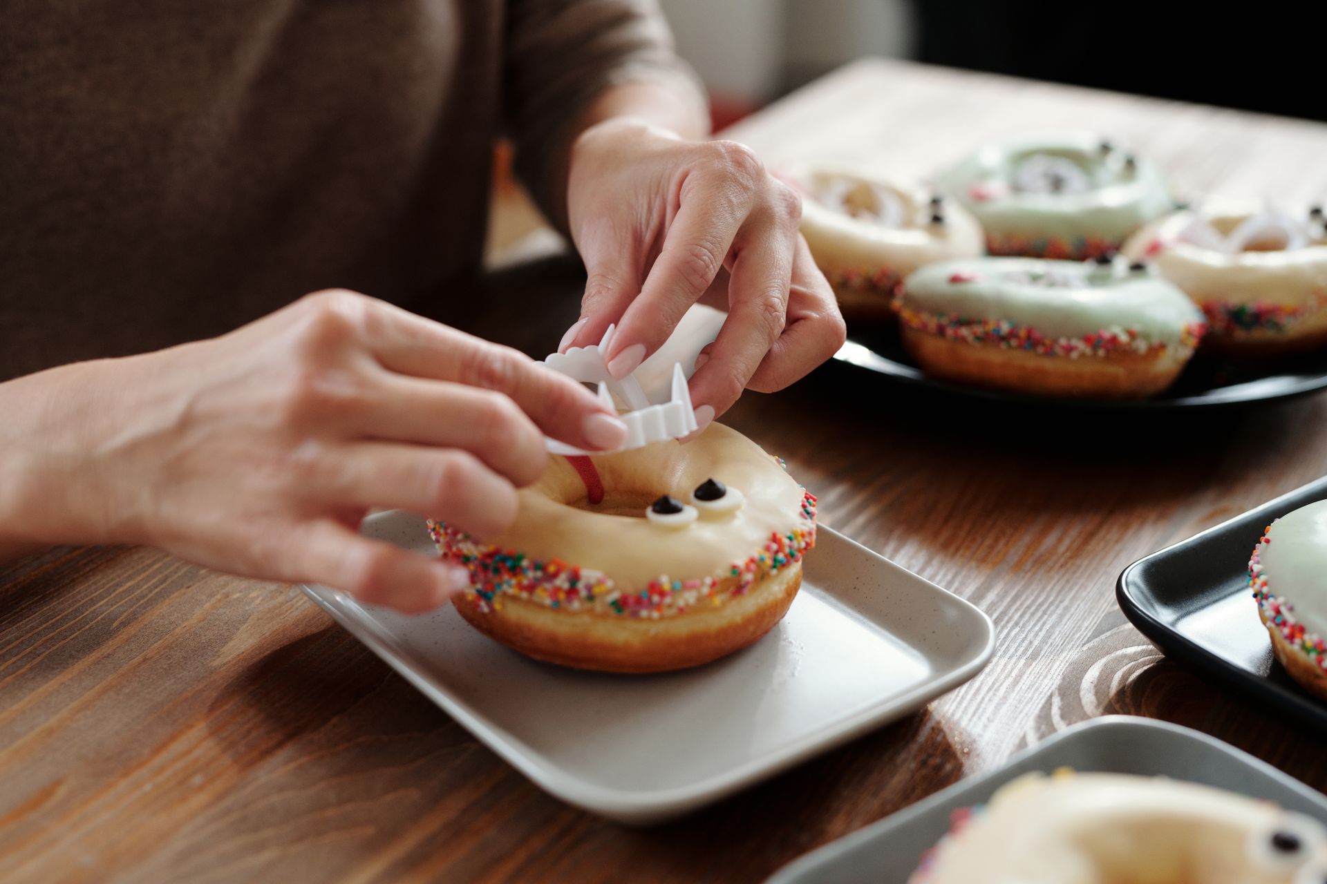 Person Putting A Plastic Vampire Teeth On A Donut