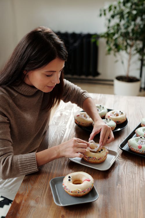 将塑料牙放在甜甜圈上的女人