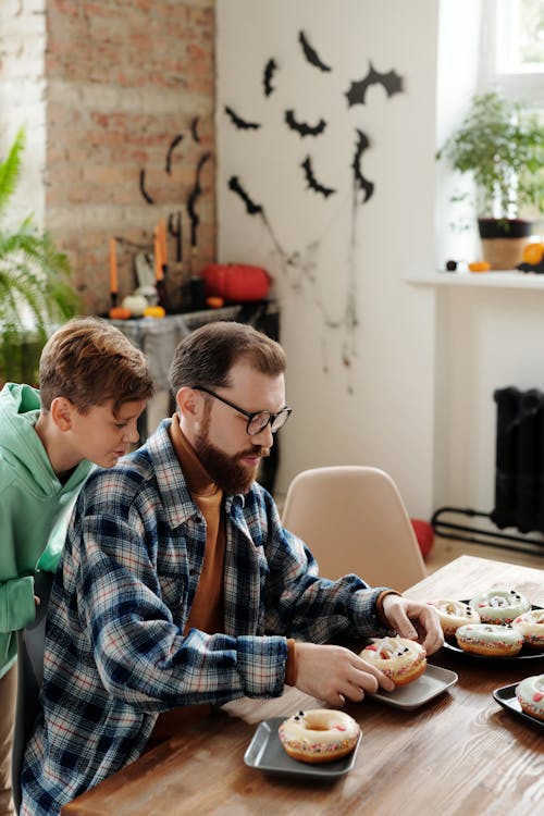 A Boy Watching His Father Put Donut In A Plate