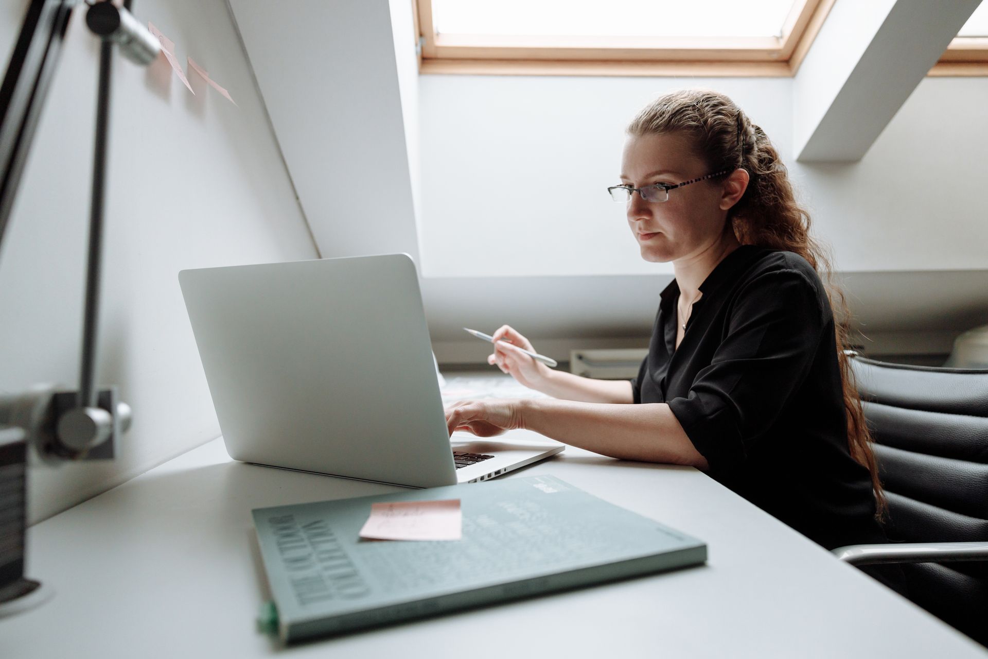 Focused woman working remotely on laptop in modern office setting
