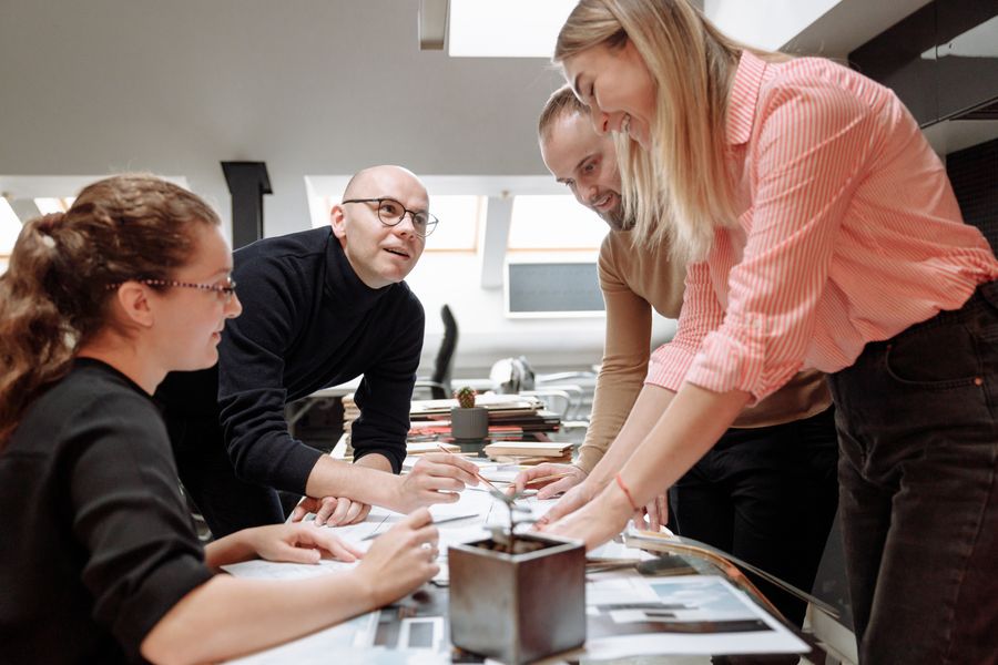 Four colleagues leaning over a desk in discussion — photo by Thirdman on Pexels