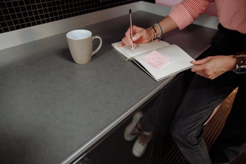 Free A Person Writing on a Notebook Stock Photo