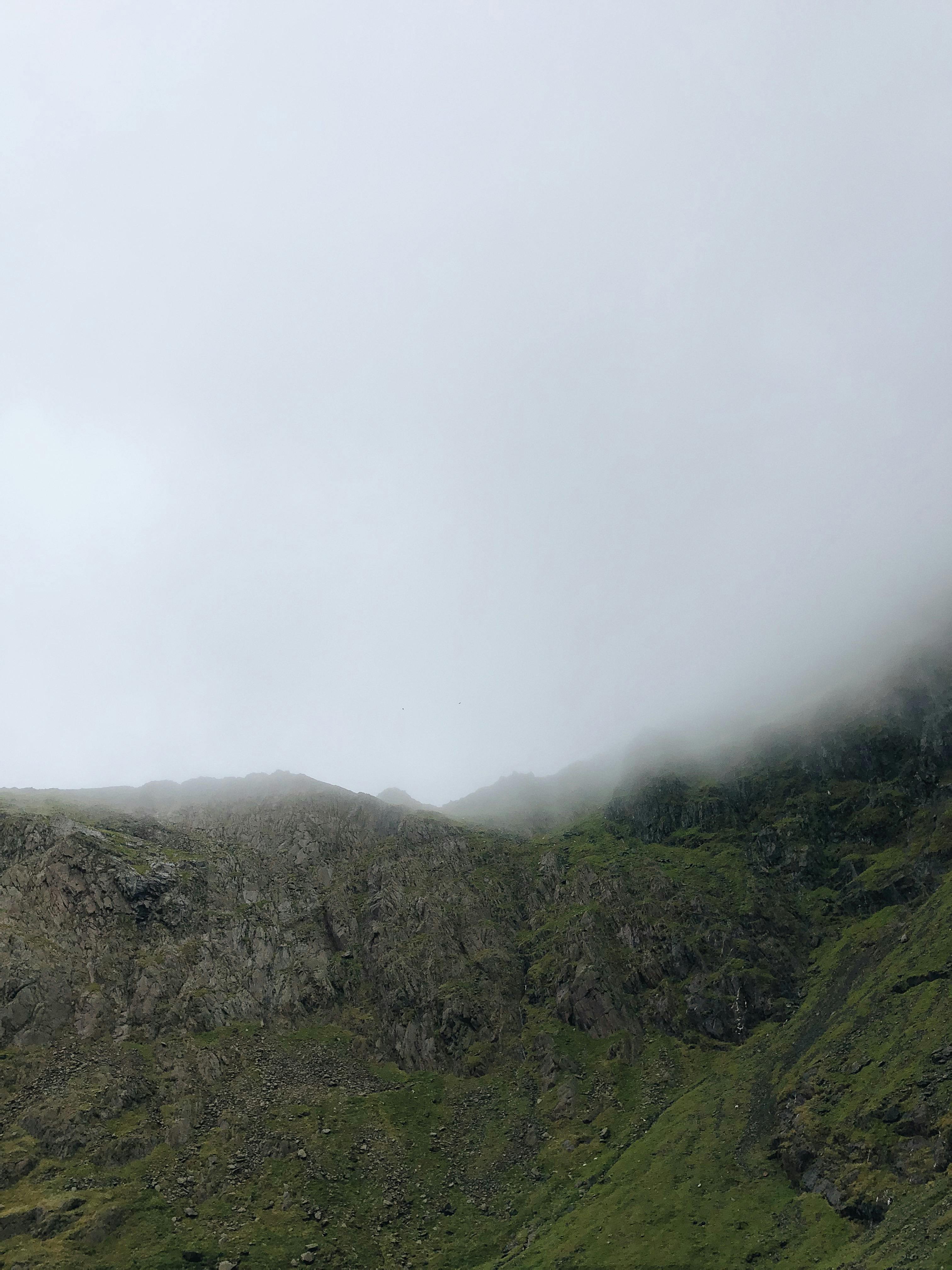 Misty view of a green mountainous region in Gwynedd, Wales, shrouded in clouds.