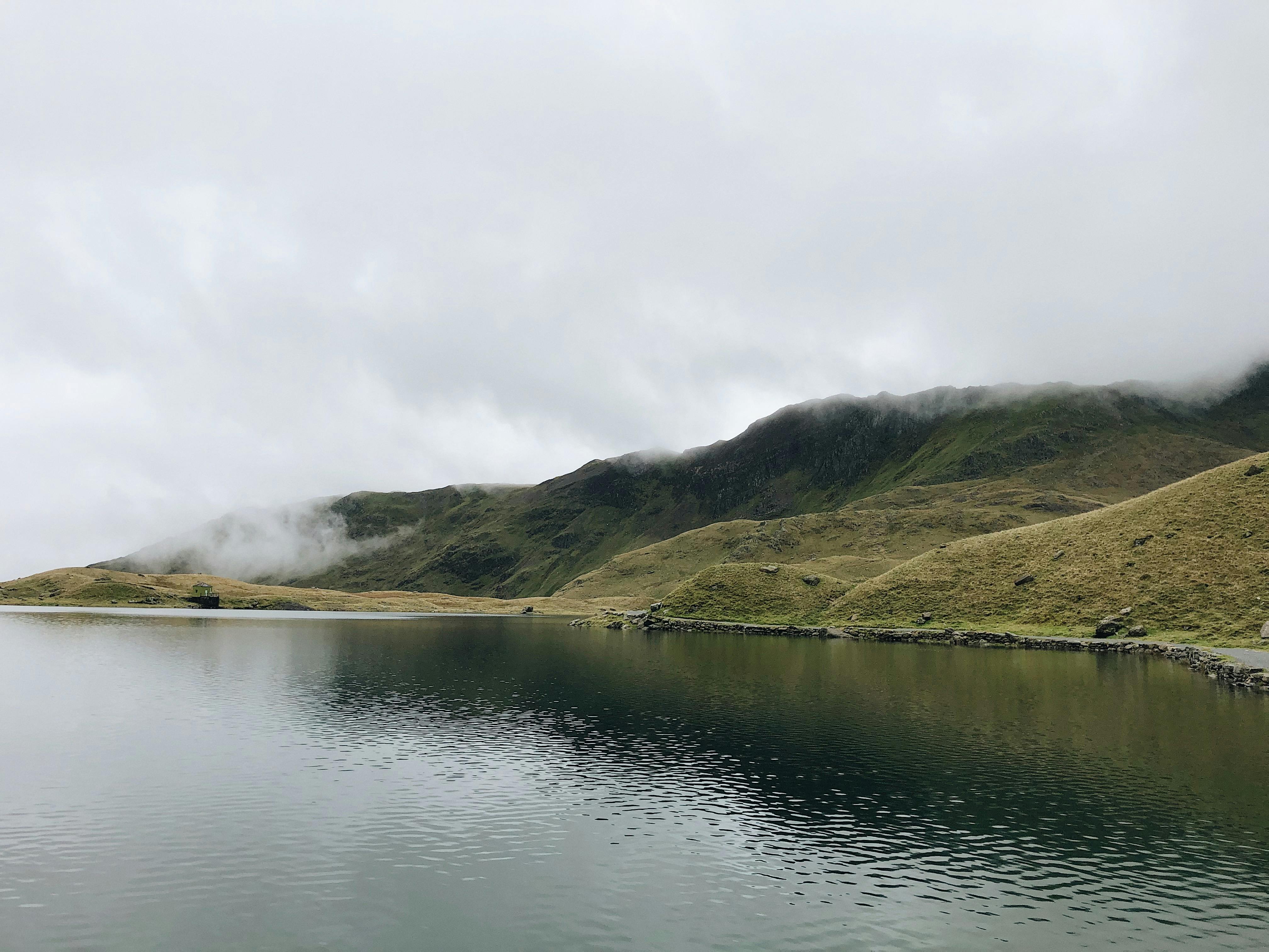 Serene lake with misty hills, captured in Gwynedd, Wales, showcasing natural beauty.