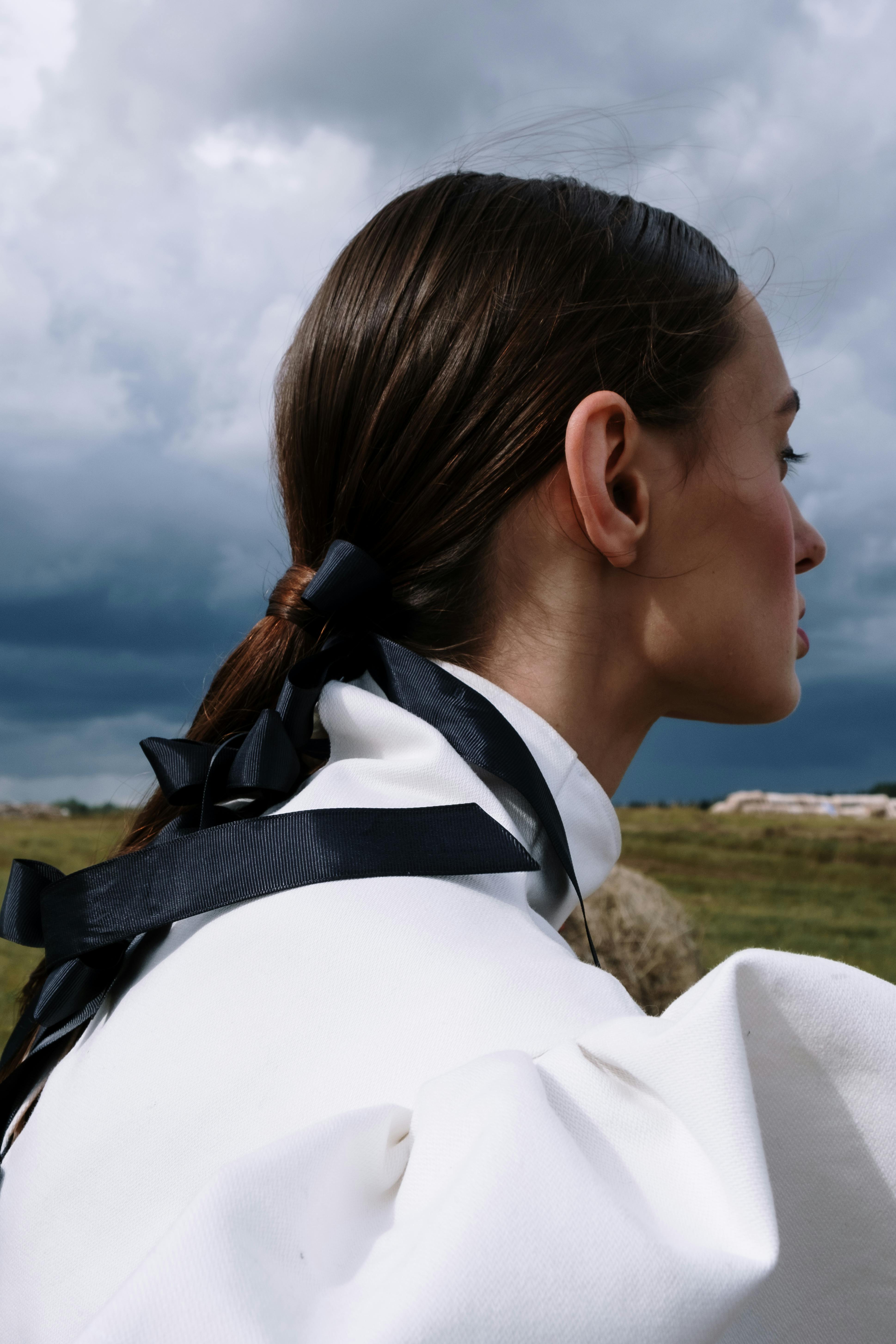 Profile of a stylish woman in a high fashion outfit with dramatic sky backdrop.