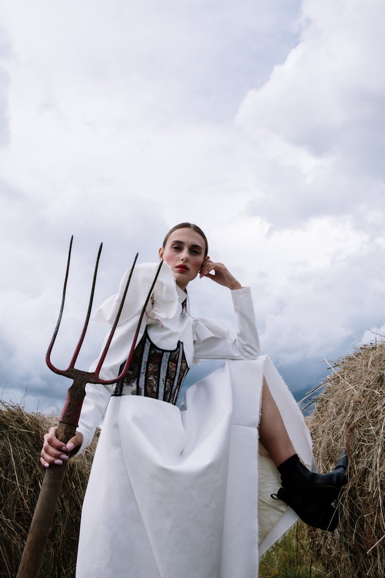 Elegant Woman In White Dress Holding A Pitchfork 