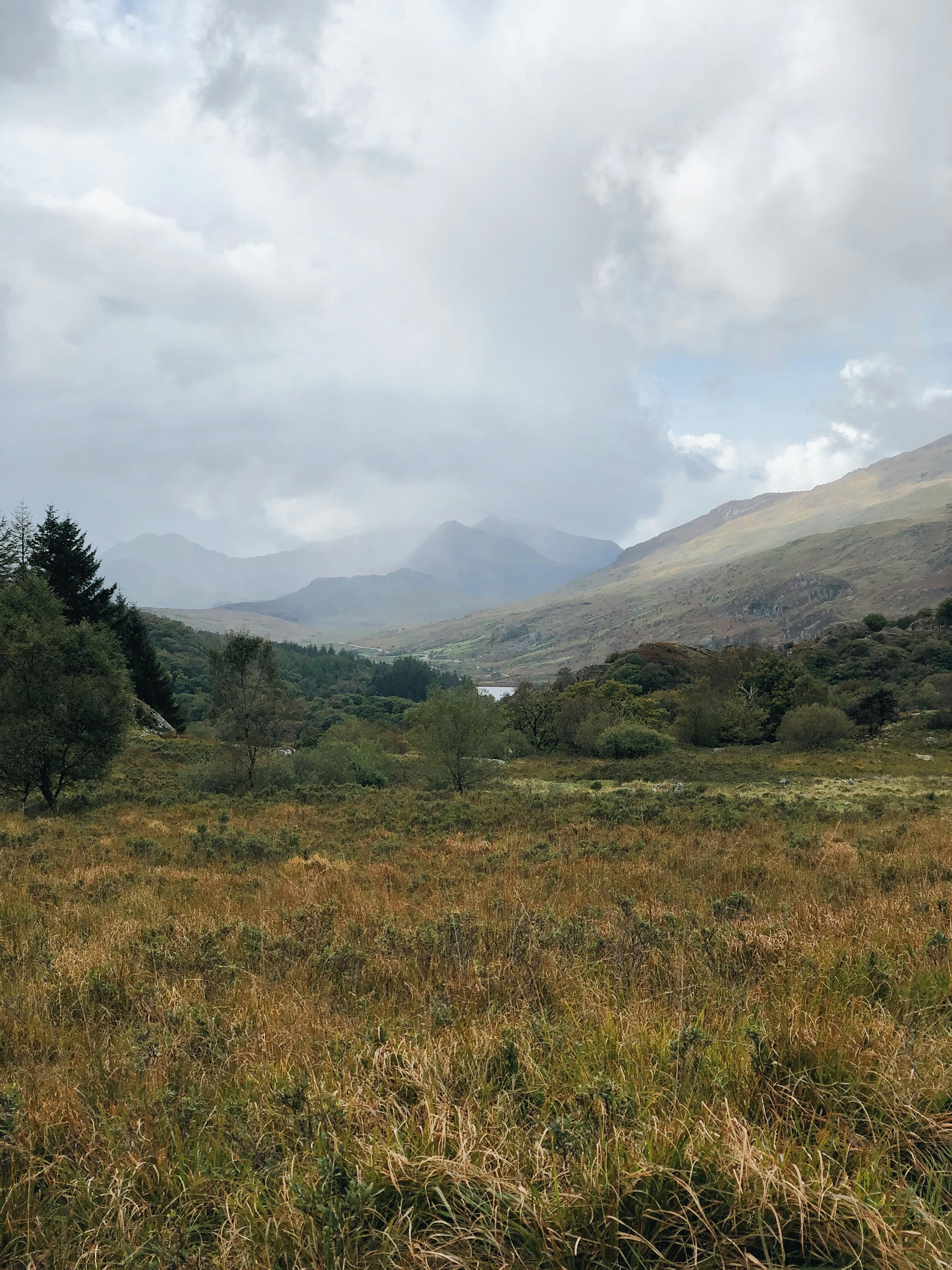Breathtaking view of mountains and fields in Conwy, Wales under a cloudy sky.