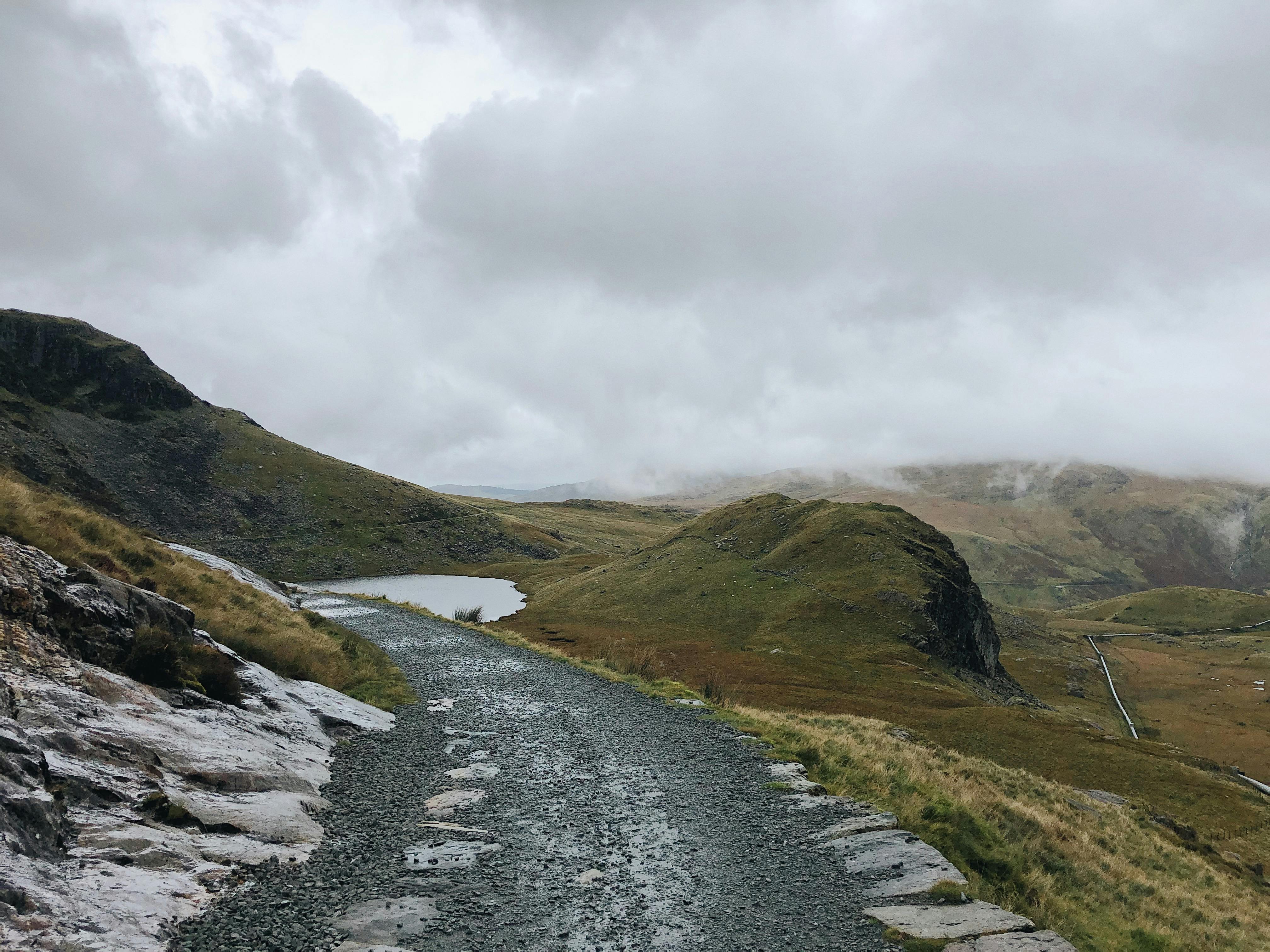 Explore the scenic misty hills and rugged pathway in Gwynedd, Wales, perfect for nature enthusiasts.
