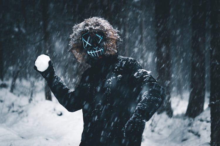 A Masked Person Holding A Snowball