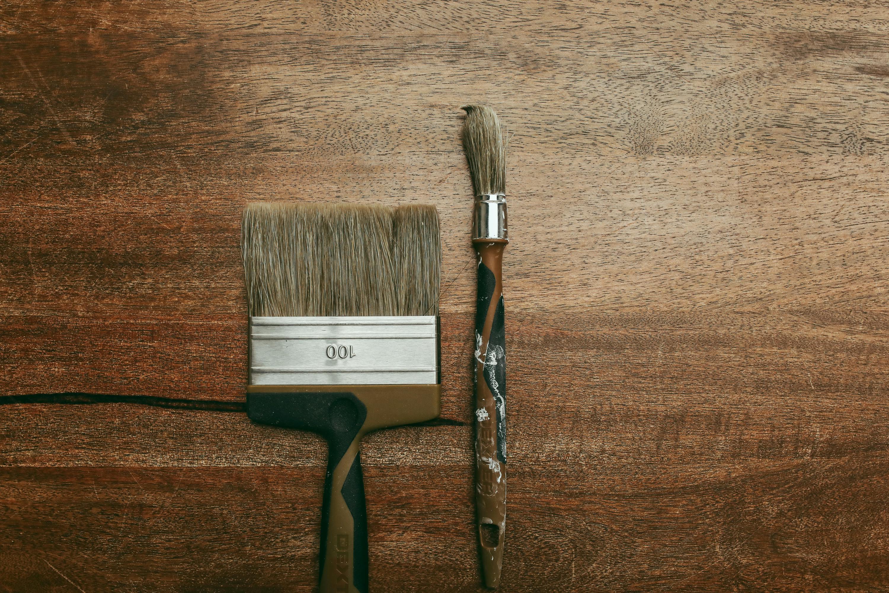 Close-up of two paintbrushes on a rustic wooden surface, perfect for creative projects.