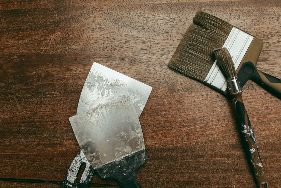 Flat lay showing paintbrushes and spatulas on a wooden surface, ideal for art and DIY themes.