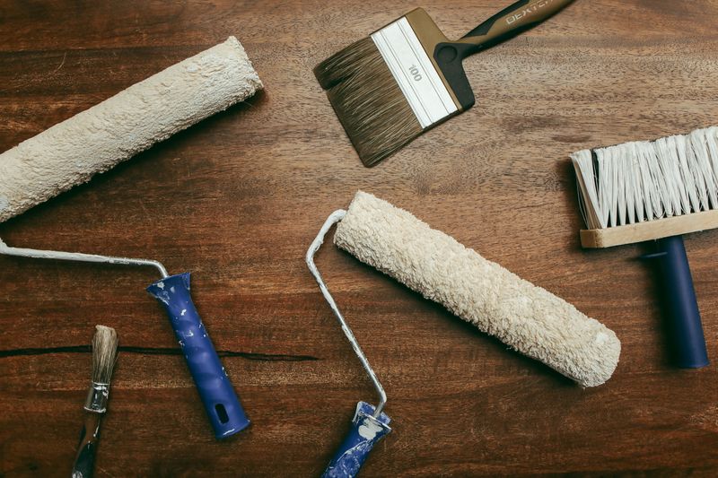 Painting rollers and brushes laid out on a wooden surface