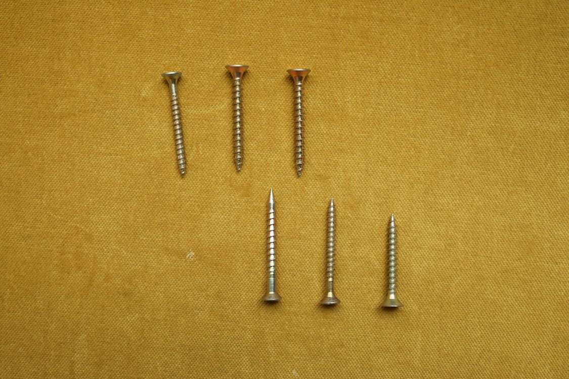 Pieces of Silver Screws on a Yellow Textile