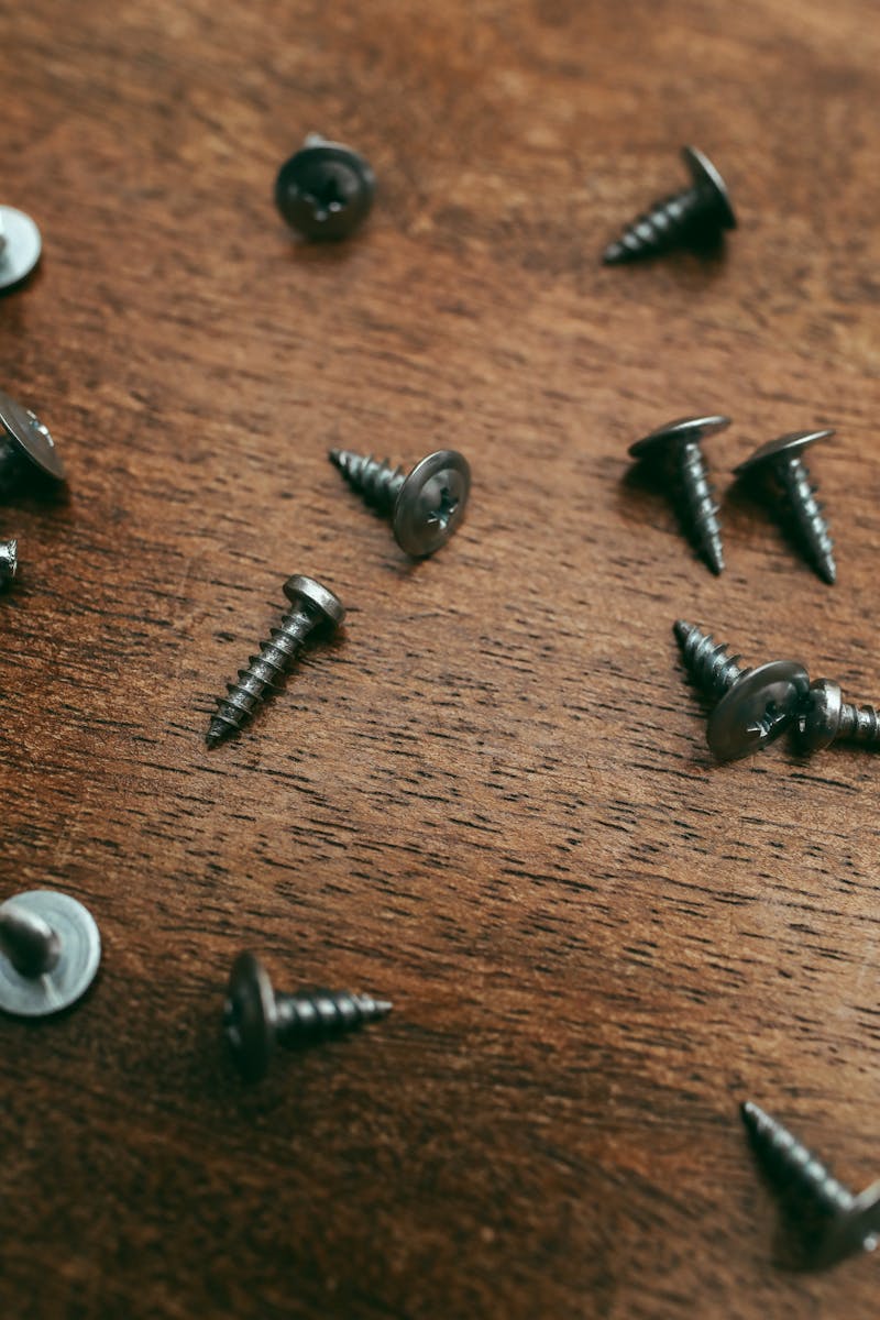 Wood Screws on a Work Surface — Various Gauges Ready for Installation Close-up of silver wood screws scattered on a textured wooden surface for DIY and construction projects