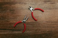 Red Handle Stainless Steel Pliers on Wooden Table