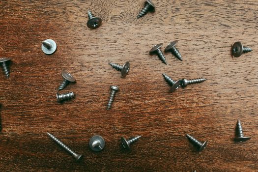A detailed view of scattered screws on a wooden table for repair or DIY projects.