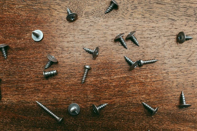 Material Comparison – Stainless Steel vs Zinc-Plated Wood Screws for Indoor and Outdoor Use Overhead view of various stainless steel and zinc-plated wood screws scattered on a wooden surface