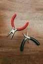 Red Handle Stainless Steel Pliers Beside Black Handle Knife